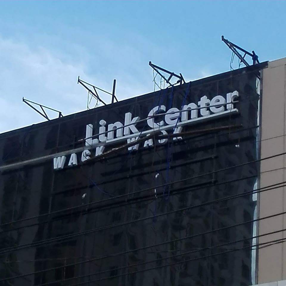 Damaged LED signage for Link Center, with partial WASH letters, in Mandaluyong. Supports bent and wires exposed. By M&G Global Ads.